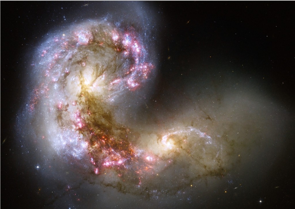 The Antennae galaxies, viewed in the sharpest-yet image of this merging pair of galaxies. During the course of their collision, billions of stars will be formed. The two spiral galaxies, about 45 million light-years from our solar system, started to interact a few hundred million years ago, making the Antennae galaxies one of the nearest and youngest examples of a pair of colliding galaxies. Nearly half of the faint objects in the Antennae image are young clusters containing tens of thousands of stars. The orange blobs are the two cores of the original galaxies and consist mainly of old stars criss-crossed by filaments of dust, which appears brown in the image. The two galaxies are dotted with brilliant blue star-forming regions surrounded by glowing hydrogen gas, appearing in the image in pink. #